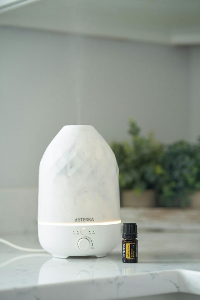 White essential oil diffuser and bottle on counter with houseplants creating a serene atmosphere.