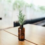A sprig of rosemary in a brown glass bottle on a wooden table, capturing simplicity and elegance.
