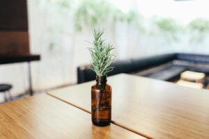 A sprig of rosemary in a brown glass bottle on a wooden table, capturing simplicity and elegance.